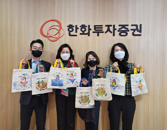 한화투자증권 임직원들이 집에서 제작한 기부물품을 들고 사진촬영을 하고 있다.(한화투자증권 제공)